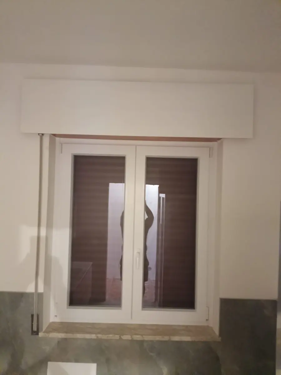 Cassonetto bianco sopra una finestra a due ante
